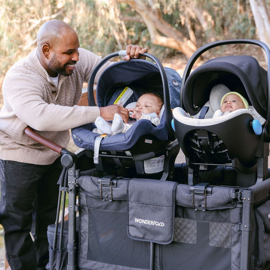 A parent clicks two infant capsules onto a WonderFold car seat adapter